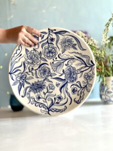 Ett unikt stort handmålat fat i porslin med blå detaljerade blommor, tillverkat av keramiker Pernilla Wetzel på Studio Kurbits